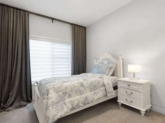 This charming bedroom features a white upholstered headboard and a matching bed frame adorned with crystal finials.