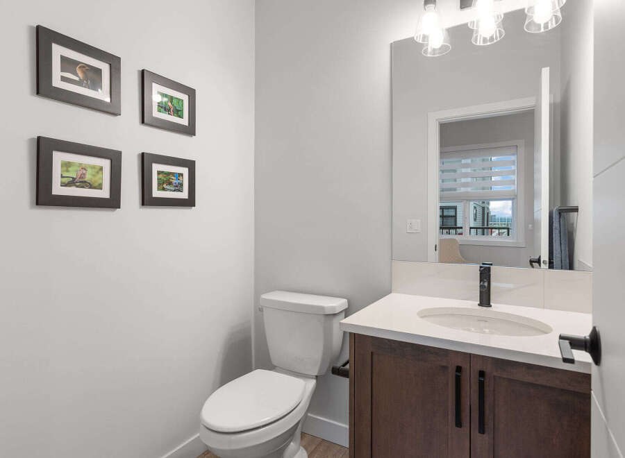 This modern bathroom features a sleek vanity with a quartz countertop and a dark wood cabinet, complemented by a stylish black faucet.