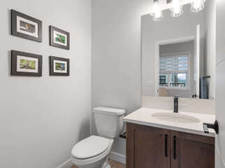 This modern bathroom features a sleek vanity with a quartz countertop and a dark wood cabinet, complemented by a stylish black faucet.