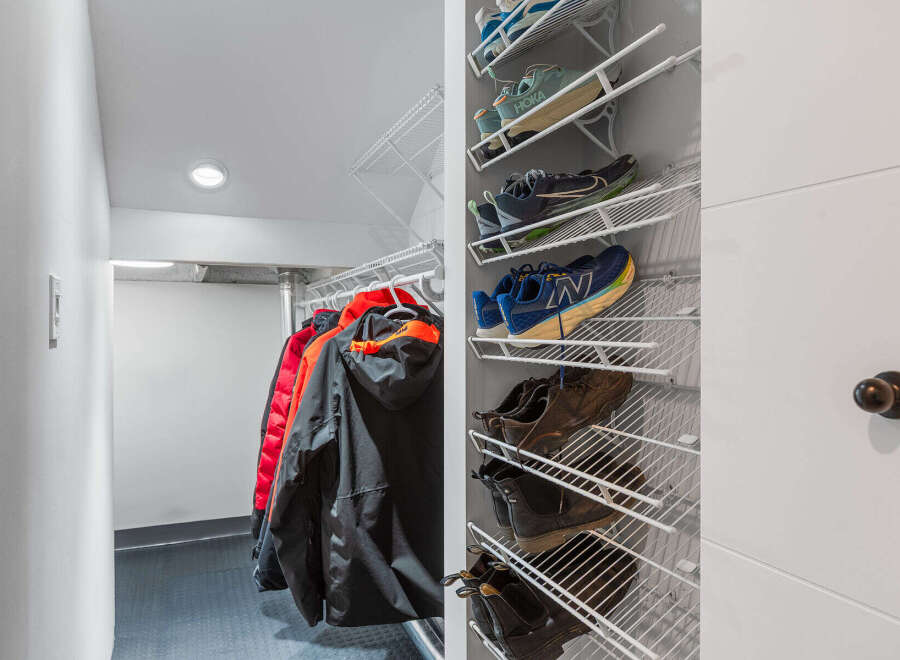 Maximize your storage with this well-organized closet featuring a multi-tiered shoe rack and ample hanging space for coats.