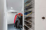 Maximize your storage with this well-organized closet featuring a multi-tiered shoe rack and ample hanging space for coats.