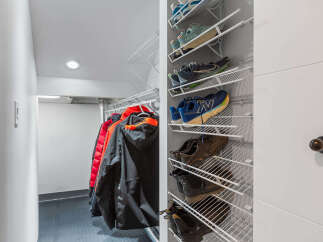 Maximize your storage with this well-organized closet featuring a multi-tiered shoe rack and ample hanging space for coats.