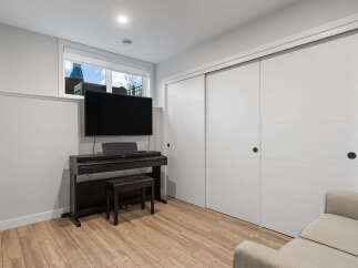 This modern living space features a sleek entertainment setup with a large flat-screen TV mounted above a digital piano and bench.