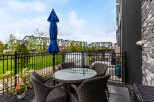 Enjoy outdoor living on this charming patio featuring a glass-top dining table with four wicker chairs and a vibrant blue umbrella.