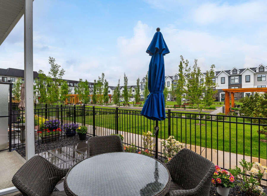 Enjoy outdoor living on this charming patio, complete with a glass-top table and comfortable wicker chairs, perfect for al fresco dining.