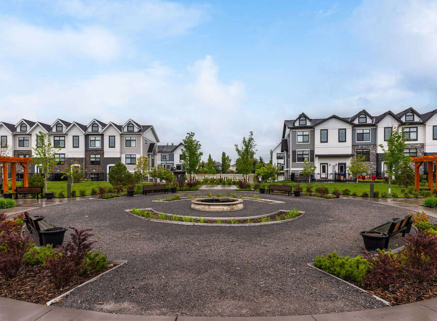 Discover modern townhome living in this vibrant community, featuring a central courtyard with a decorative fountain and ample seating.