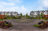Discover modern townhome living in this vibrant community, featuring a central courtyard with a decorative fountain and ample seating.
