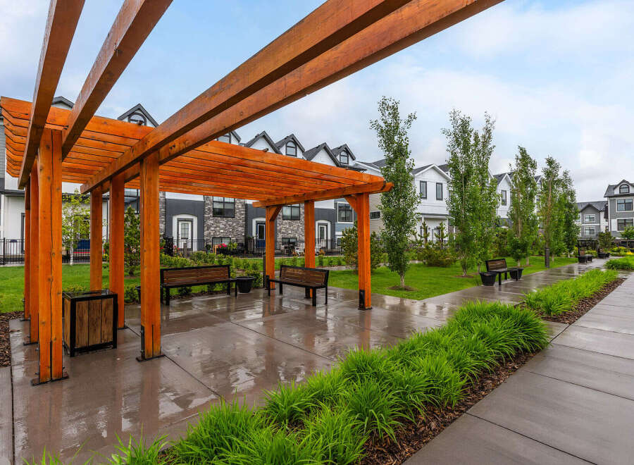 Discover modern living in this stunning townhouse community, featuring a beautifully landscaped courtyard with a wooden pergola and ample seating.