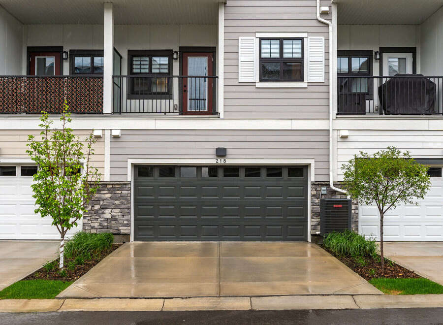 Discover modern living in this townhouse featuring a sleek dark gray garage door and a charming balcony with decorative screening.
