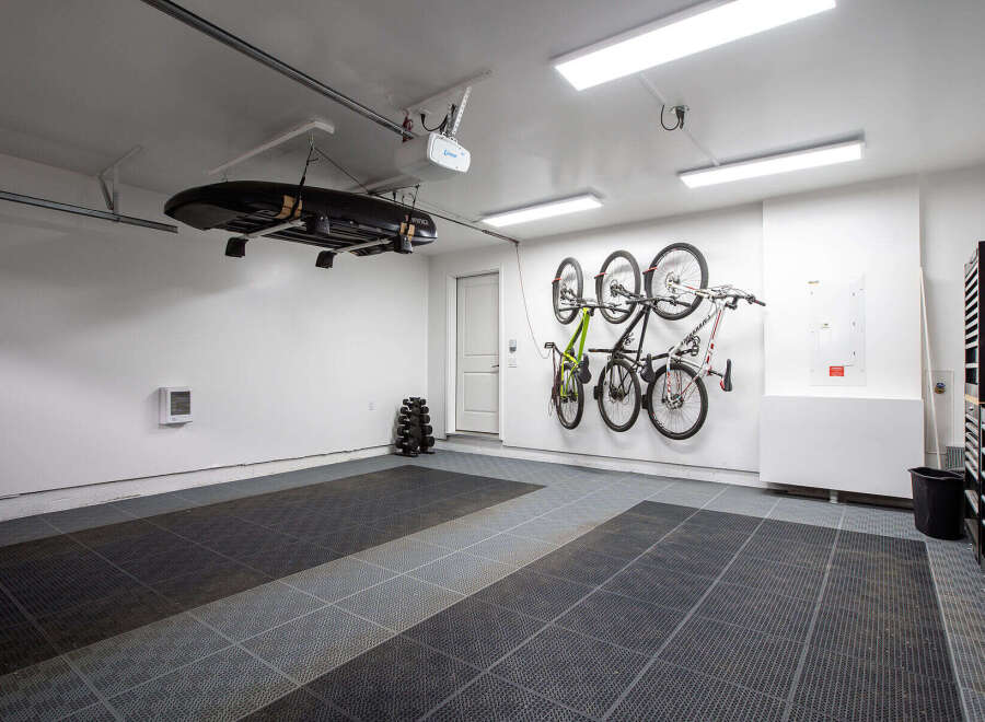 This spacious garage offers excellent storage solutions, featuring a ceiling-mounted rack for a cargo box and wall-mounted racks for multiple bicycles.