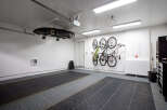 This spacious garage offers excellent storage solutions, featuring a ceiling-mounted rack for a cargo box and wall-mounted racks for multiple bicycles.