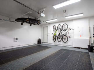 This spacious garage offers excellent storage solutions, featuring a ceiling-mounted rack for a cargo box and wall-mounted racks for multiple bicycles.