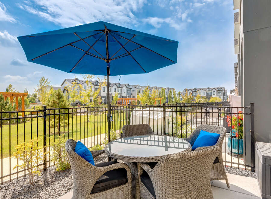 Enjoy outdoor living with this charming patio featuring a round glass-top table and four wicker chairs, perfect for al fresco dining.