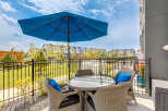 Enjoy outdoor living with this charming patio featuring a round glass-top table and four wicker chairs, perfect for al fresco dining.
