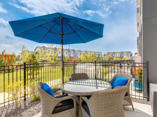 Enjoy outdoor living with this charming patio featuring a round glass-top table and four wicker chairs, perfect for al fresco dining.