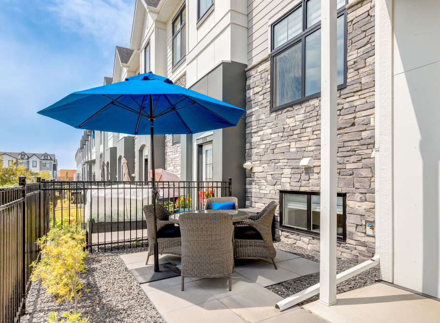 Enjoy outdoor living on this charming patio featuring a blue umbrella and comfortable wicker seating.