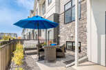 Enjoy outdoor living on this charming patio featuring a blue umbrella and comfortable wicker seating.