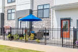 Enjoy outdoor living with this charming patio featuring a vibrant blue umbrella and comfortable seating, perfect for relaxing or entertaining.