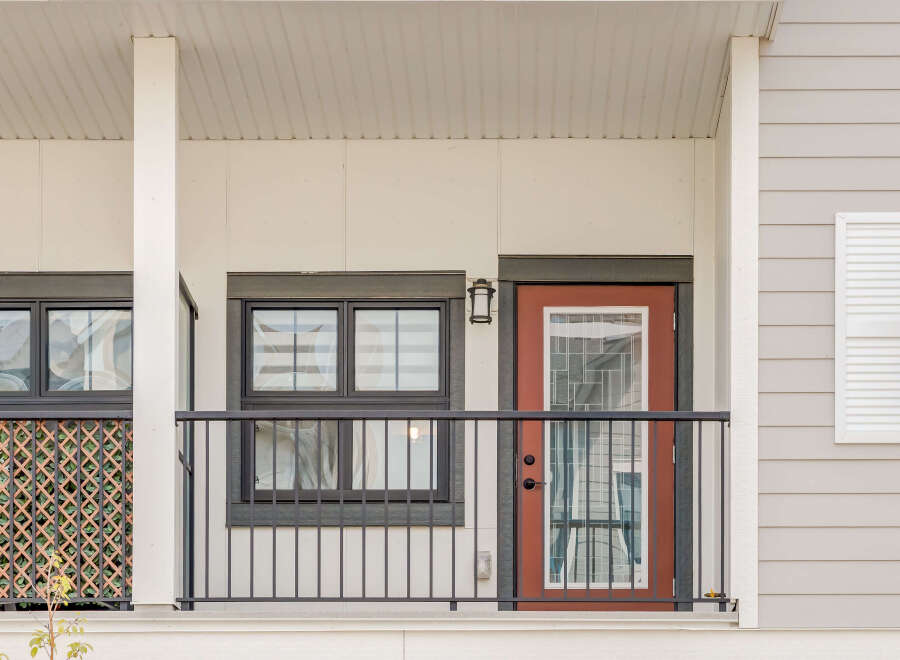 This charming property features a welcoming covered porch with a stylish red door and large windows, perfect for enjoying the outdoors.