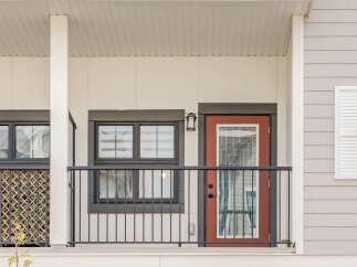 This charming property features a welcoming covered porch with a stylish red door and large windows, perfect for enjoying the outdoors.