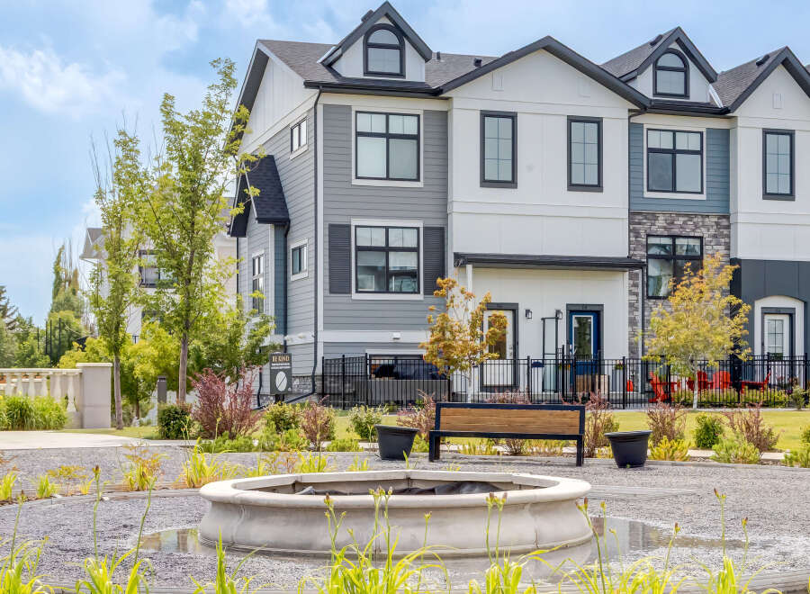 Discover modern townhome living with this stunning property featuring a multi-tone exterior of gray siding and white panels, accented by stone details.