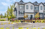 Discover modern townhome living with this stunning property featuring a multi-tone exterior of gray siding and white panels, accented by stone details.