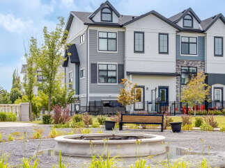 Discover modern townhome living with this stunning property featuring a multi-tone exterior of gray siding and white panels, accented by stone details.