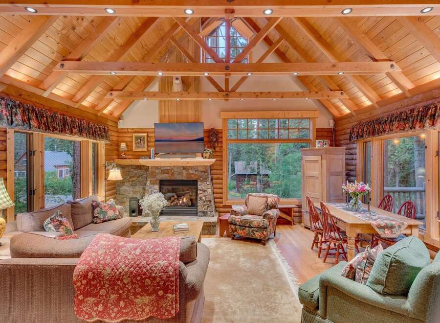 Experience rustic charm in this stunning log cabin living room, featuring a grand stone fireplace and soaring vaulted ceilings with exposed beams.