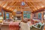 Experience rustic charm in this stunning log cabin living room, featuring a grand stone fireplace and soaring vaulted ceilings with exposed beams.
