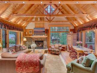 Experience rustic charm in this stunning log cabin living room, featuring a grand stone fireplace and soaring vaulted ceilings with exposed beams.