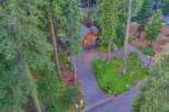 Nestled amidst towering trees, this stunning property offers a secluded retreat with a charming wooden home featuring a prominent gable window and a spacious attached garage.