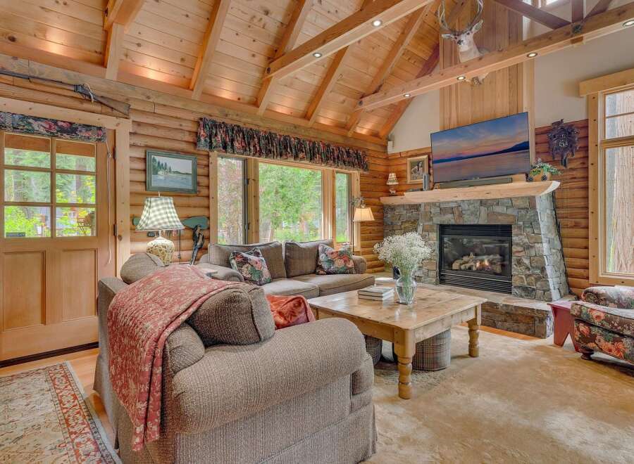 Experience rustic charm in this inviting log cabin living room, featuring a grand stone fireplace perfect for cozy evenings.