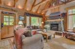 Experience rustic charm in this inviting log cabin living room, featuring a grand stone fireplace perfect for cozy evenings.