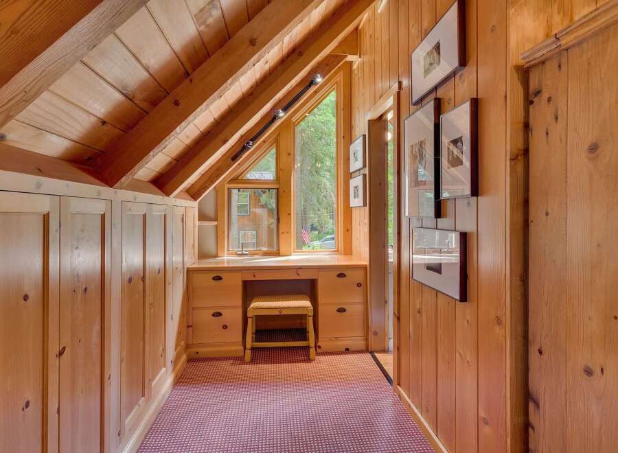 Discover this charming attic space featuring a built-in wooden desk and ample storage cabinets, perfect for a cozy home office or reading nook.