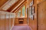 Discover this charming attic space featuring a built-in wooden desk and ample storage cabinets, perfect for a cozy home office or reading nook.
