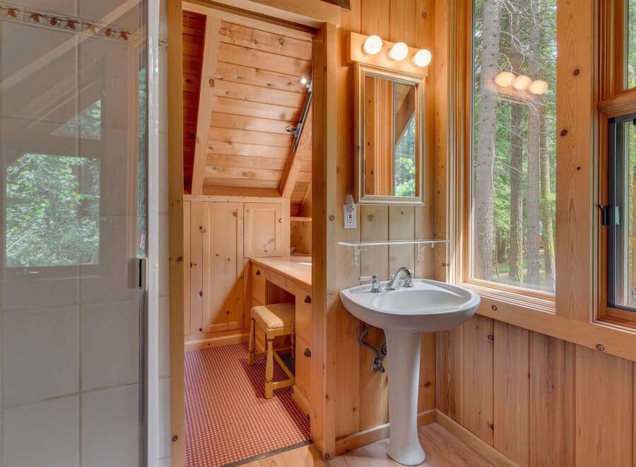 Experience rustic charm in this cozy bathroom featuring a pedestal sink and a vanity area with ample storage.