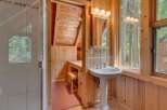 Experience rustic charm in this cozy bathroom featuring a pedestal sink and a vanity area with ample storage.