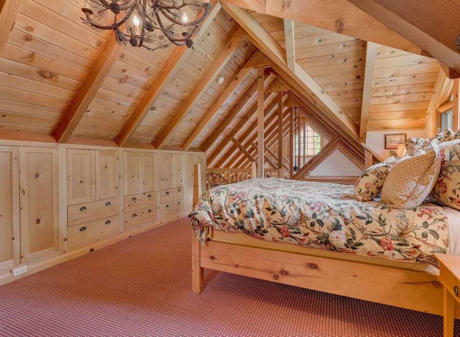 Discover this charming attic bedroom featuring a rustic wooden bed adorned with a floral comforter and matching pillows.