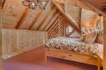 Discover this charming attic bedroom featuring a rustic wooden bed adorned with a floral comforter and matching pillows.