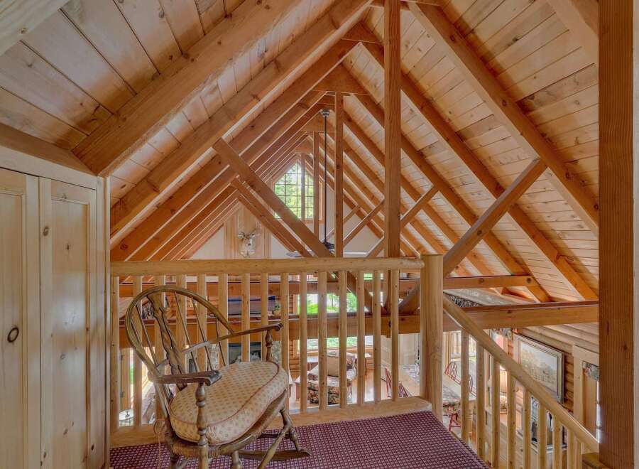 Experience rustic charm in this loft area, featuring a cozy rocking chair overlooking the living space below.