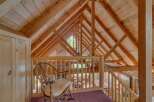 Experience rustic charm in this loft area, featuring a cozy rocking chair overlooking the living space below.
