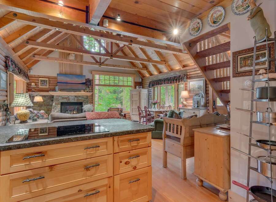 Experience rustic charm in this stunning log cabin featuring a vaulted wood-beamed ceiling and a cozy stone fireplace.