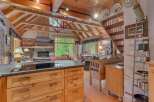 Experience rustic charm in this stunning log cabin featuring a vaulted wood-beamed ceiling and a cozy stone fireplace.