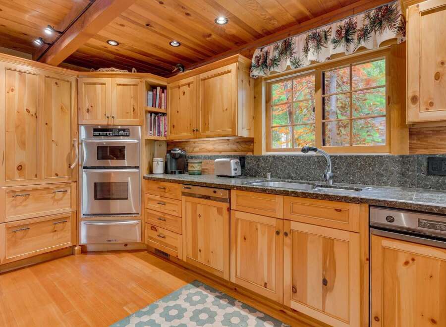 This charming kitchen features warm, natural wood cabinetry and a matching wooden ceiling with exposed beams.