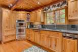 This charming kitchen features warm, natural wood cabinetry and a matching wooden ceiling with exposed beams.
