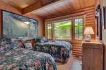 Experience rustic charm in this cozy cabin bedroom featuring two floral-print twin beds and a large scenic mural.