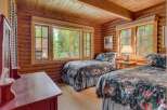 This charming log cabin bedroom features two cozy twin beds adorned with a beautiful floral comforter, perfect for a restful night's sleep.