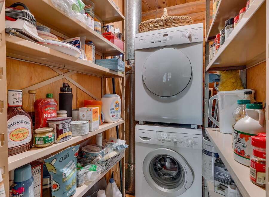Discover ample storage solutions in this pantry, featuring well-organized shelves stocked with pantry essentials and cleaning supplies.