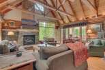 Experience rustic charm in this cozy living room featuring a grand stone fireplace and a vaulted wood-beamed ceiling.
