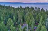 Nestled amidst a lush pine forest, this property offers a serene escape with breathtaking views of a distant lake and mountains.